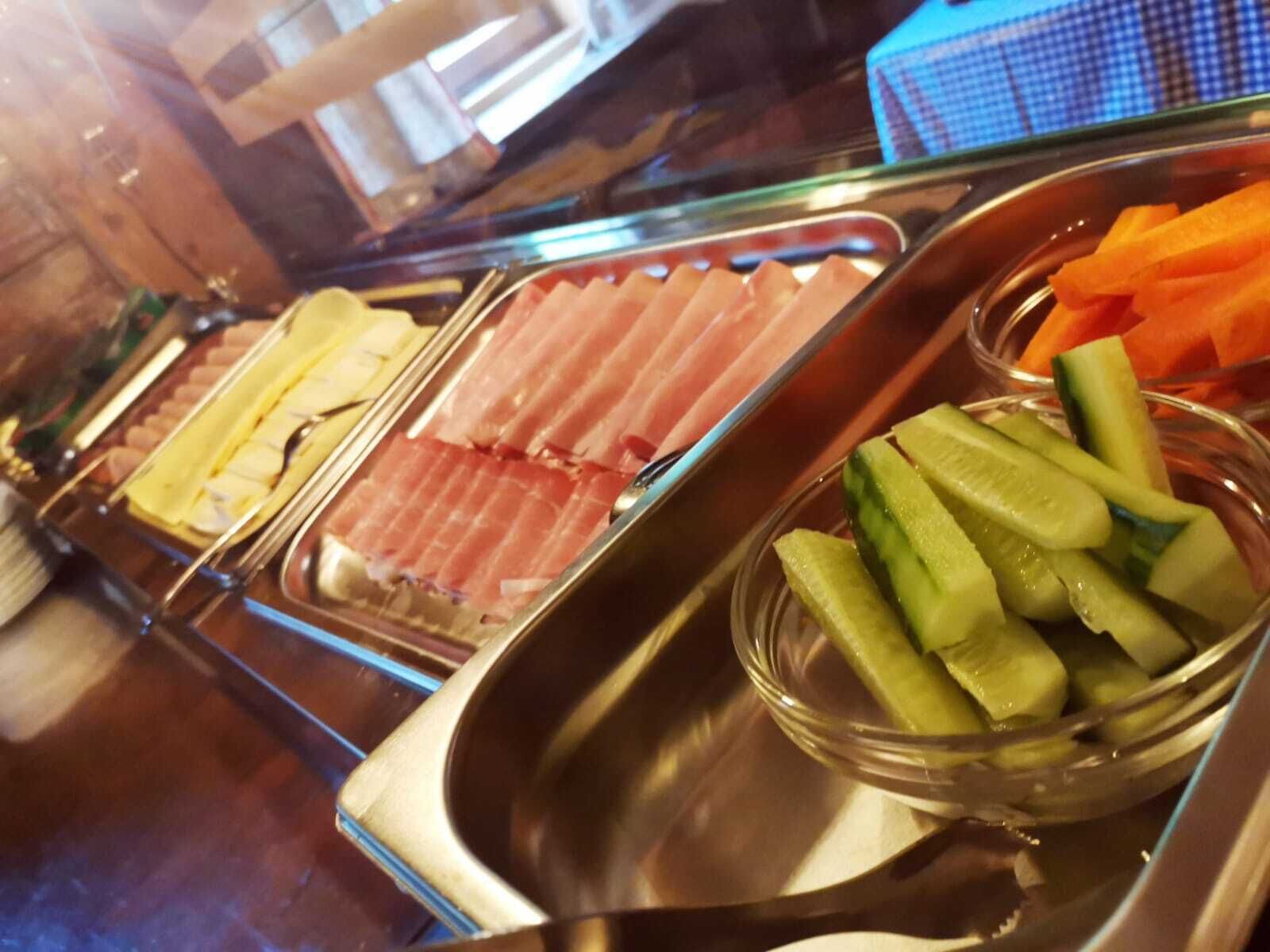 En buffé med ett varierat utbud av mat, inklusive skivad kött och inlagda grönsaker.