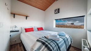 A bedroom with a bed, a window with a view, a radiator, and a shelf. - Blue View Cabin 6B with Hot Tub (Bláskógabyggd)