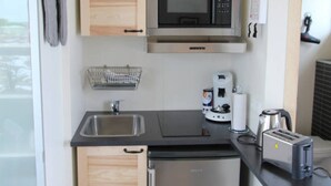 A compact kitchen with wooden cabinets, a stainless steel refrigerator, a microwave, a coffee maker, and a toaster. - Blue View Cabin 6B with Hot Tub (Bláskógabyggd)