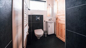 A compact bathroom with a toilet, sink, and mirror. - Blue View Cabin 6B with Hot Tub (Bláskógabyggd)