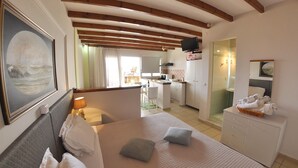 A hotel room with a bed, a desk, a television, and a bathroom visible through an open door. - Tango Studios (Corfu)