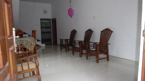 A dining area with wooden chairs and a table, a clock on the wall, and a door leading to another room. - Mango House (Talalla)