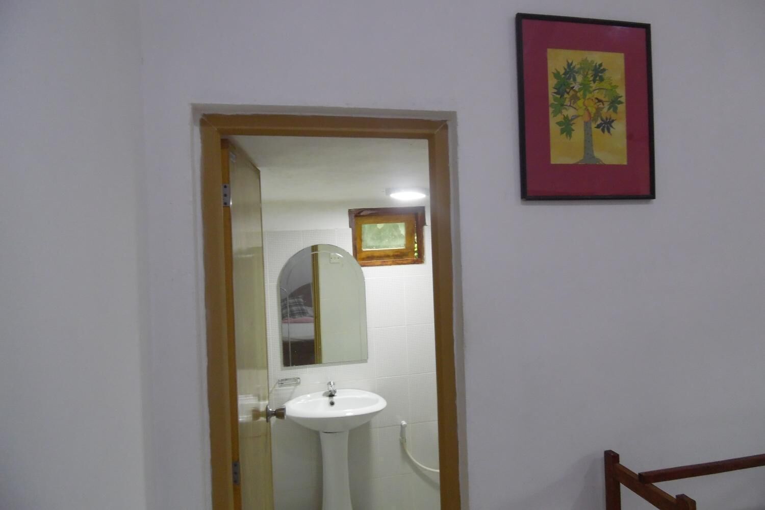 A bathroom with a white sink, a mirror, and a framed picture on the wall.
