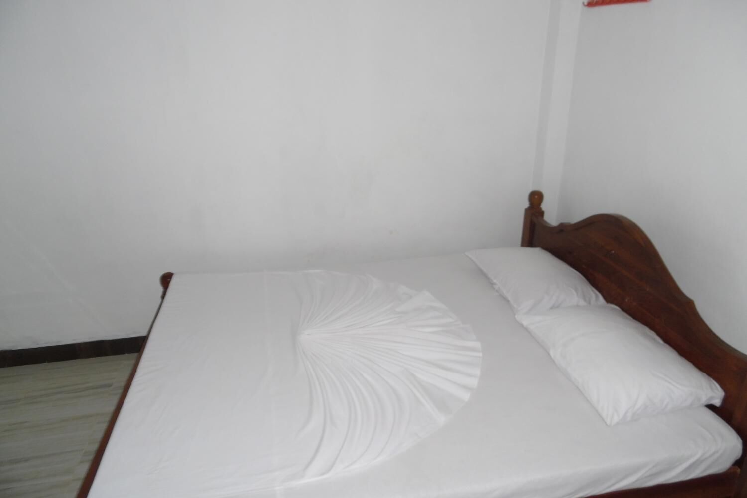 A bed with a wooden headboard and white bedding.