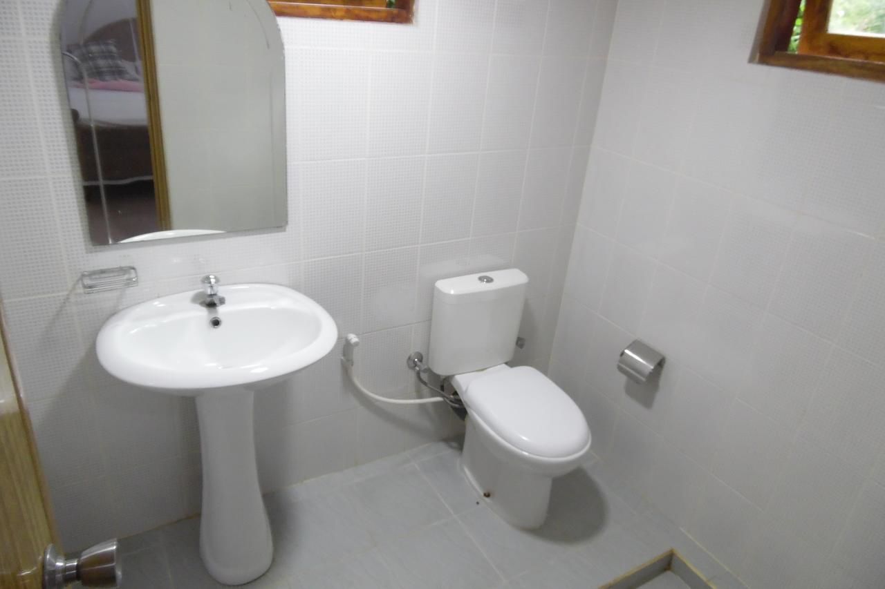 A small, clean bathroom with a white sink, toilet, and mirror.