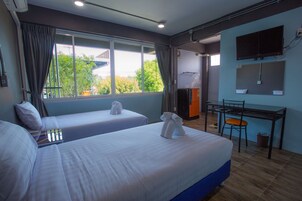 Habitación de hotel con dos camas, un escritorio, un televisor y una ventana con cortinas.