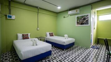 A room with two beds, a small table, and a chair. There is a picture on the wall and a window with a view of a waterfall.