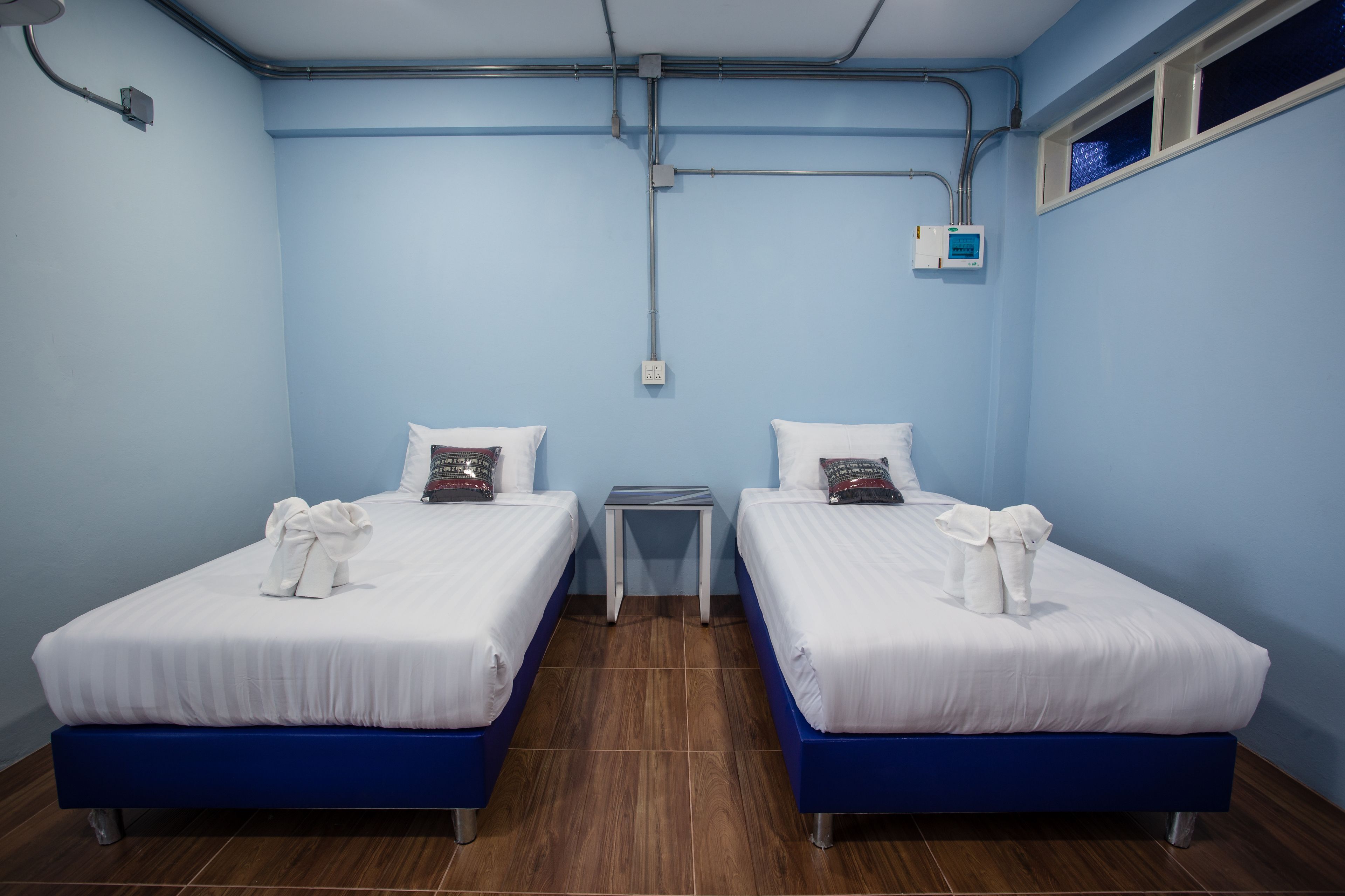 Habitación de hotel con dos camas, una mesita y un ventanal.