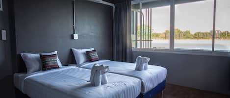 Habitación de hotel con dos camas, un ventanal grande y vistas al exterior.