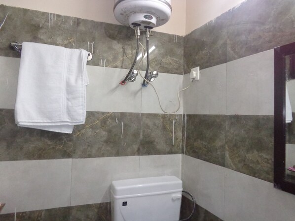 A bathroom with a shower, toilet, and a towel hanging on the wall.