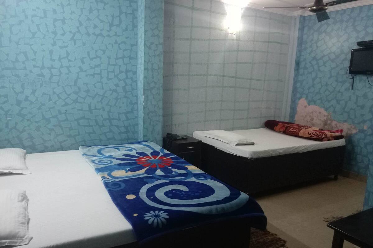 A bedroom with two beds, a ceiling fan, and a TV mounted on the wall.
