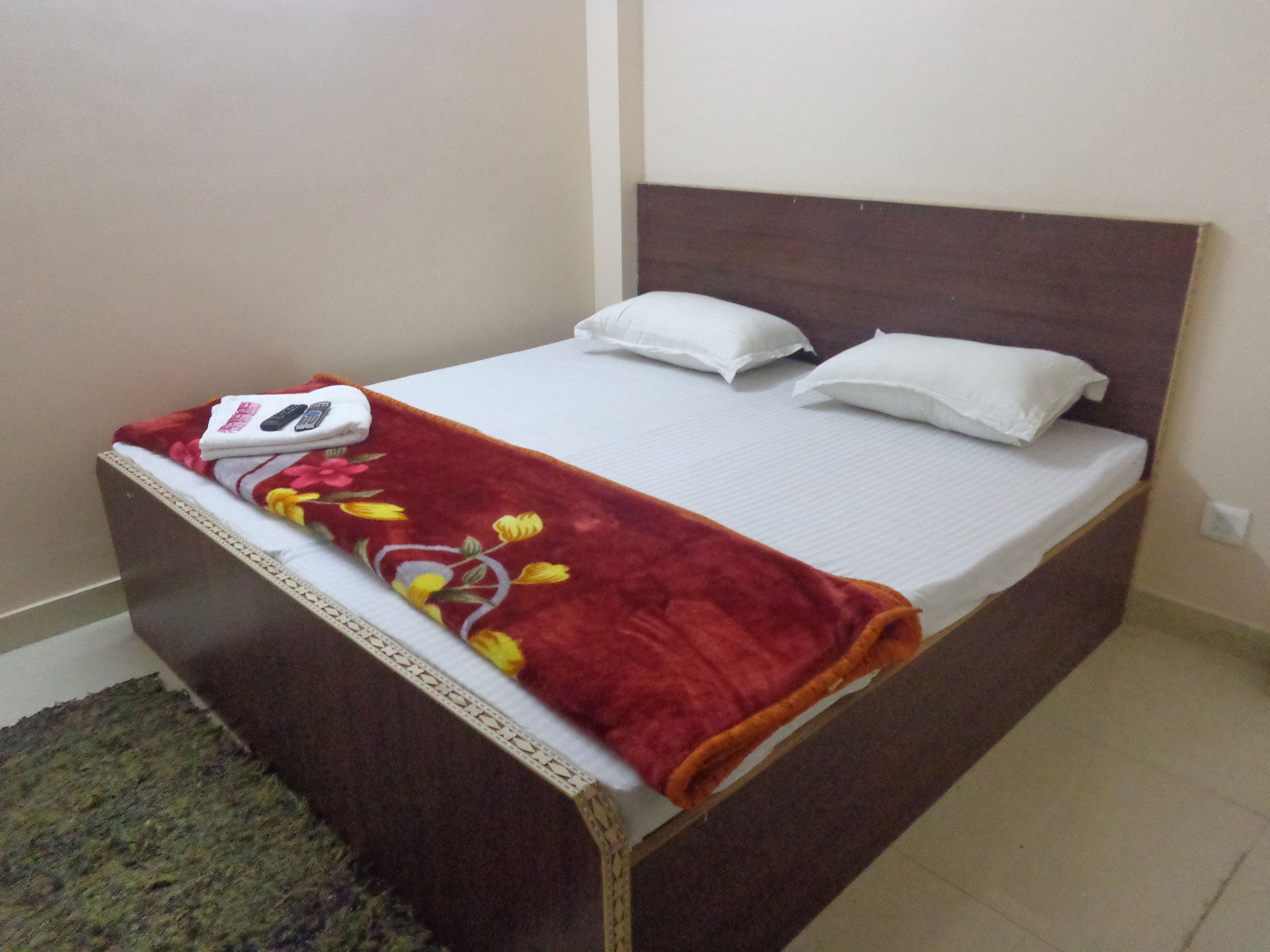 A single bed with a red blanket, white pillows, and a white bedspread.