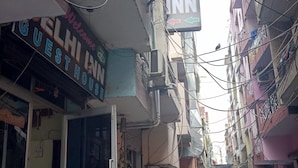 A narrow street with buildings on either side, a sign for 'Delhi Inn' indicating a guesthouse, and several motorcycles parked along the street. - Delhi Inn (New Delhi)