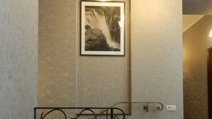 Un couloir orné d’un tableau encadré au mur, d’une plante en pot et d’un lustre.
