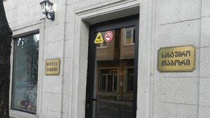 Un bâtiment avec une porte noire, une enseigne indiquant « HÔTEL TABORI » et un panneau interdisant le stationnement.