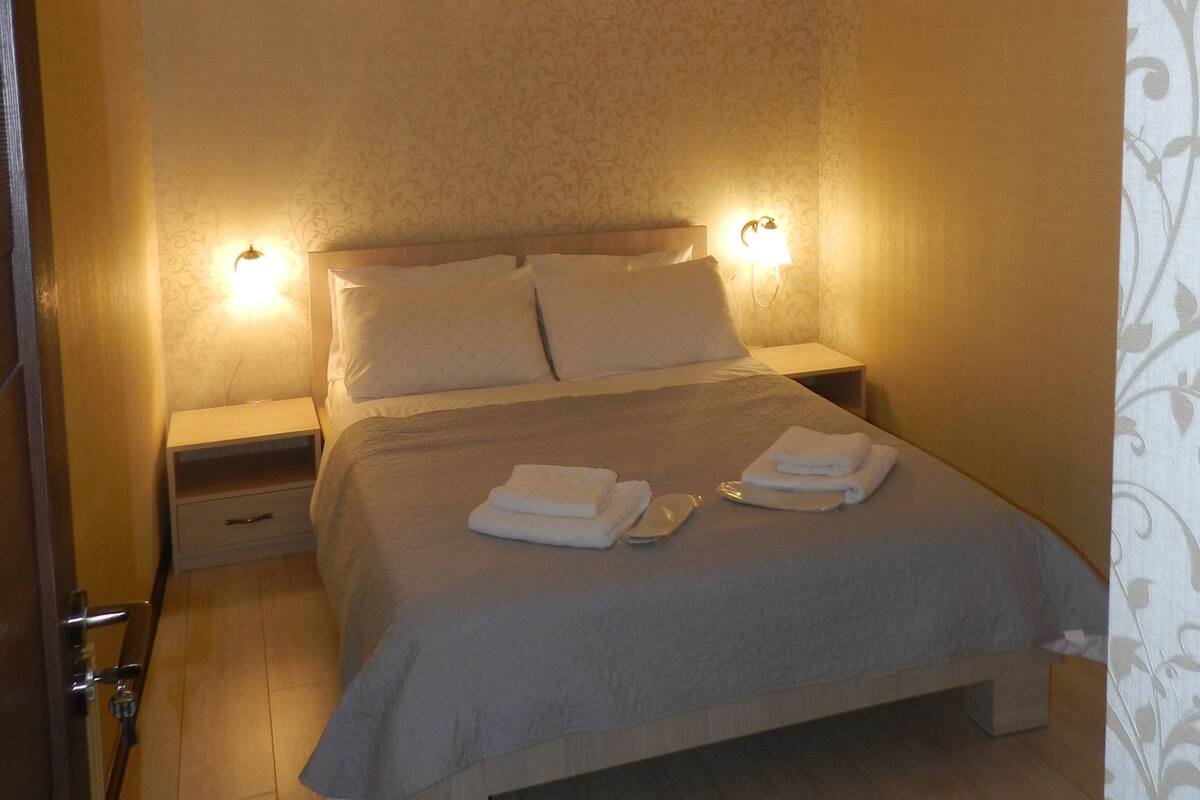 A bedroom with a bed, two bedside tables, and a nightstand.