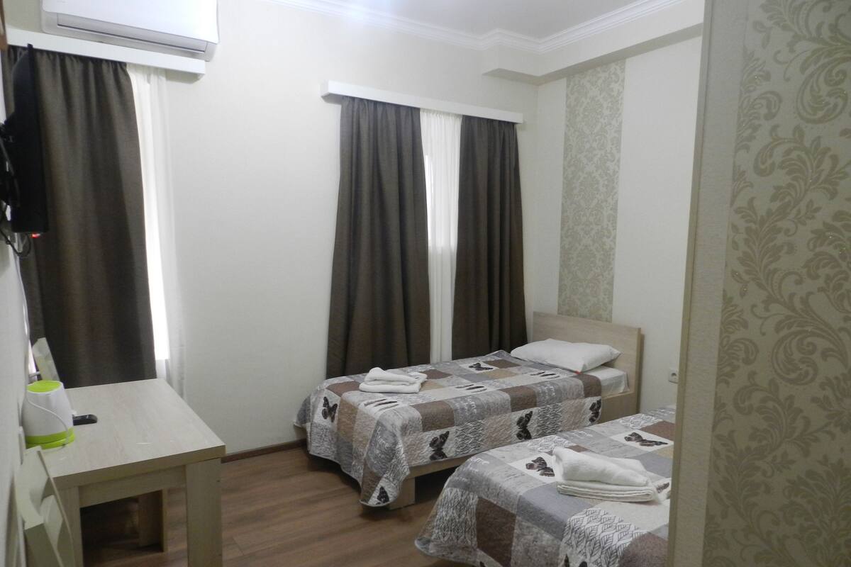 A hotel room with two beds, a desk, and a chair.