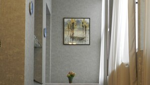 Un couloir doté d’un sol en marbre, d’une œuvre d’art encadrée au mur et d’une petite table sur laquelle est posé un vase de fleurs.