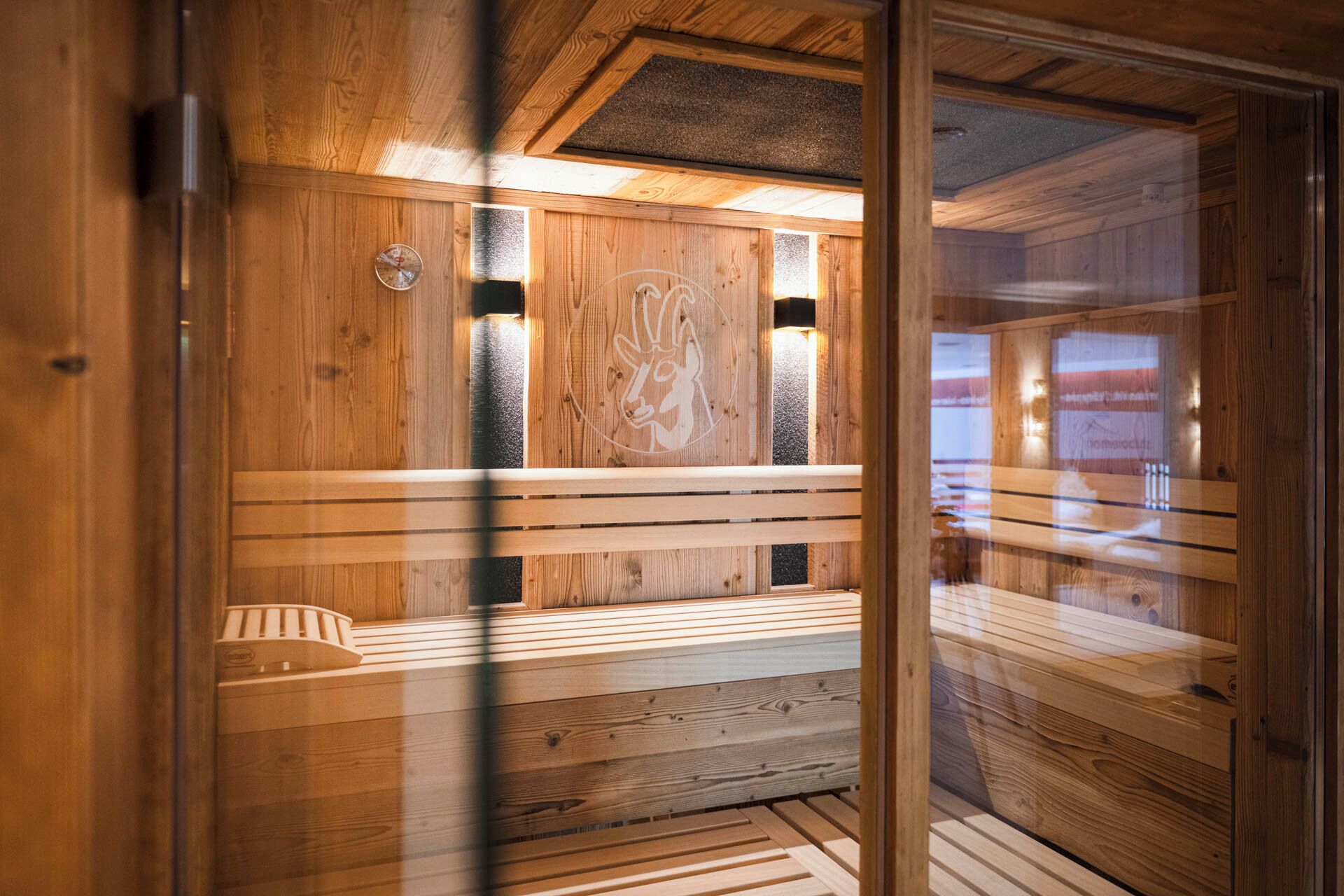 A sauna room with wooden benches and a wall-mounted sauna head.