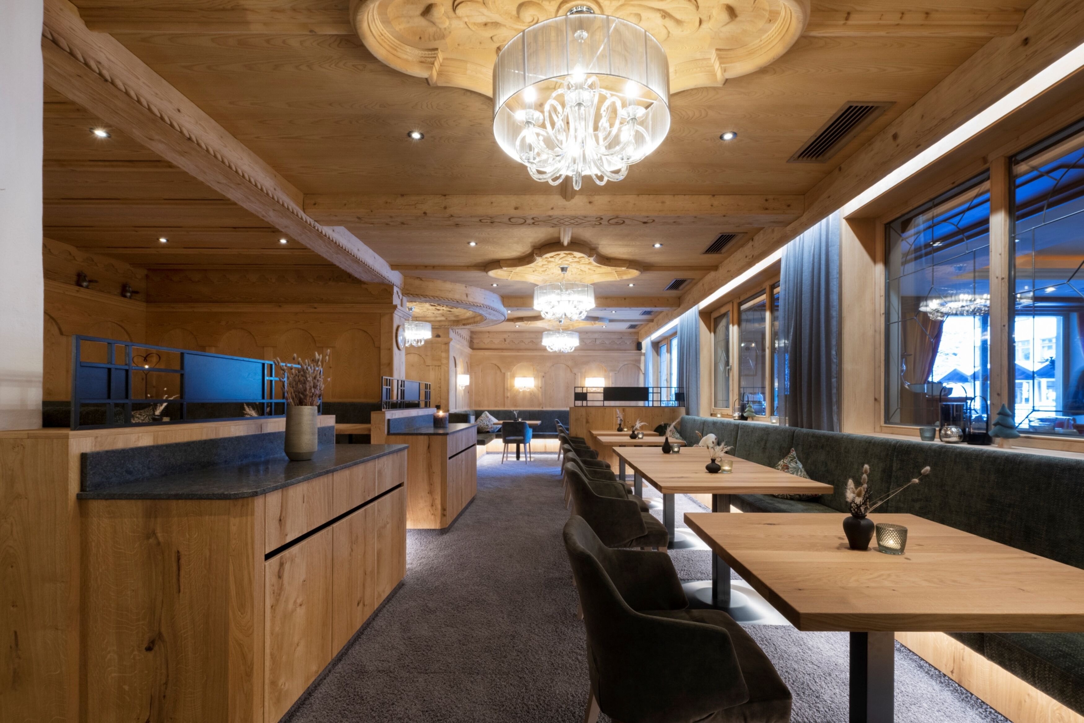 Un interior de restaurante moderno con paneles de madera, una zona de bar central y diferentes disposiciones de mesas.