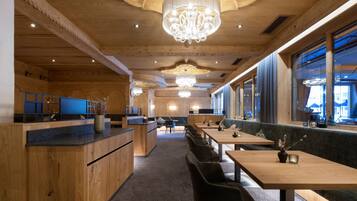 Un interior de restaurante moderno con paneles de madera, una zona de bar central y diferentes disposiciones de mesas.