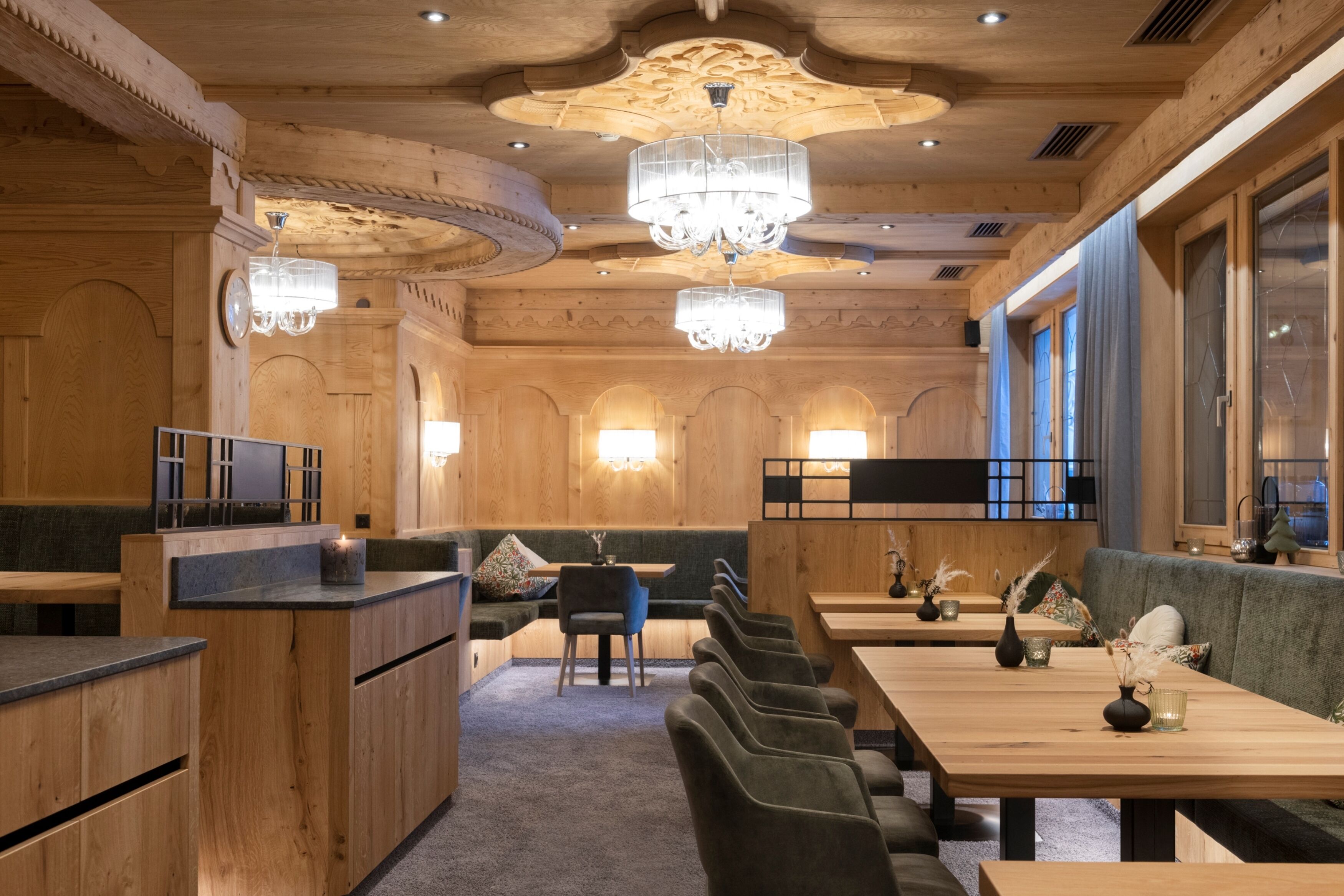 A wooden interior with high ceilings, chandeliers, and seating areas.