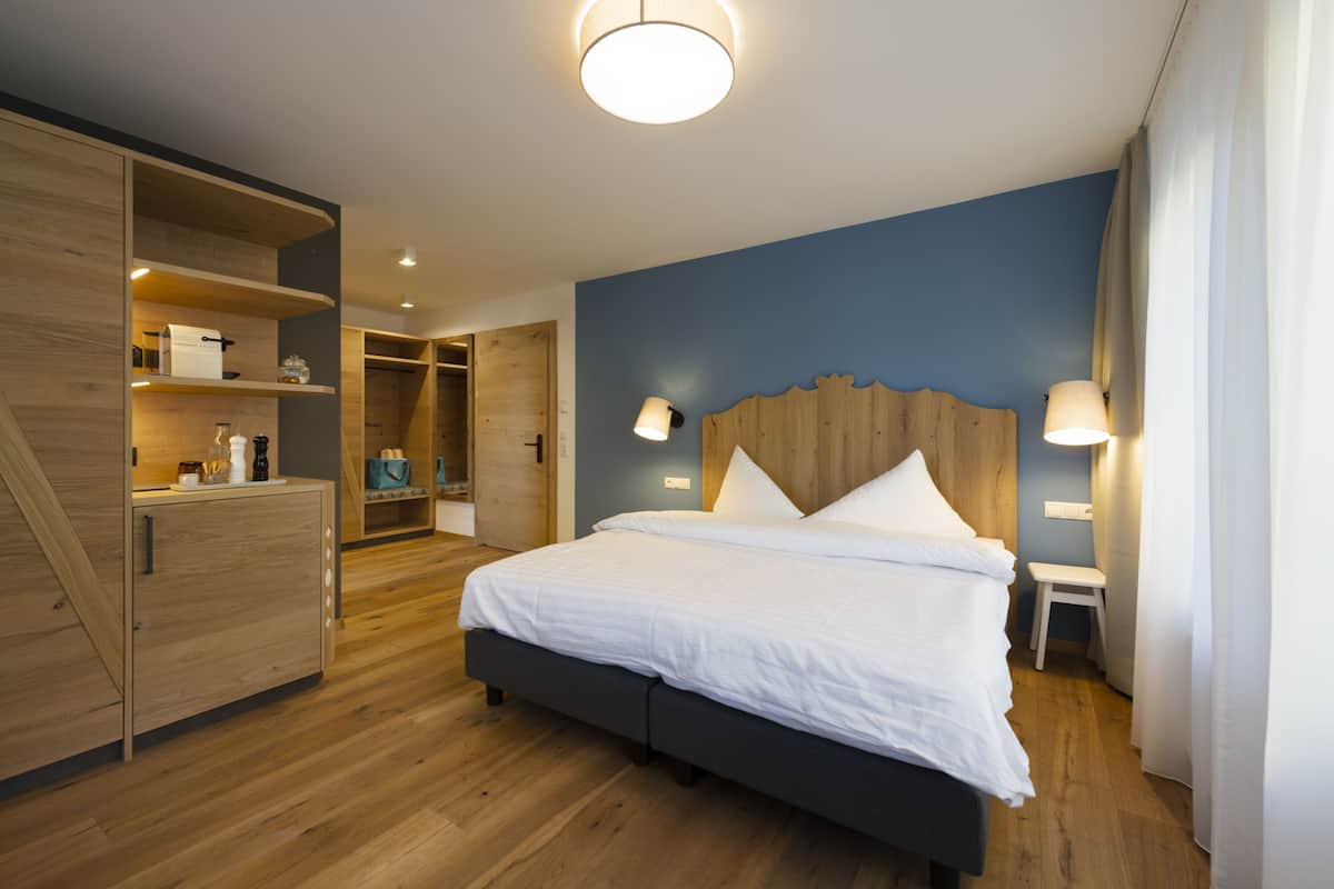 Une chambre d’hôtel moderne avec un grand lit, une armoire en bois et des étagères intégrées.