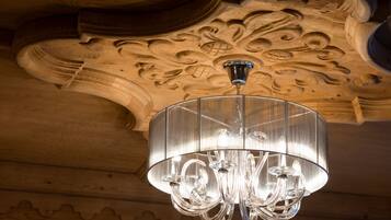 Um candelabro com cúpula de vidro transparente pendurado em um teto de madeira com esculturas detalhadas.