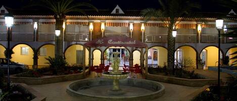 A courtyard with a fountain, red chairs, and a restaurant named "Hotel Conventillo" with a tiled roof and arches.