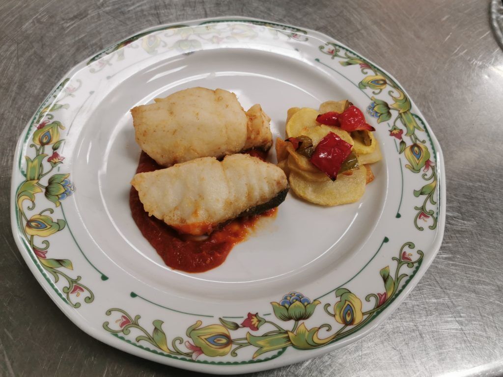 A plate with two stuffed cabbage rolls and a side of sliced vegetables.