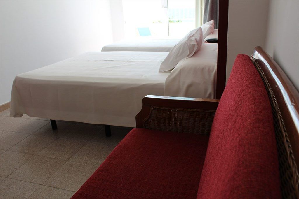 Een hotelkamer met twee bedden, een rode bank en een raam met uitzicht.