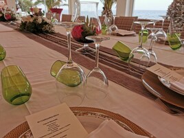 A table set for a meal with a menu card, glasses, and a view of the ocean.