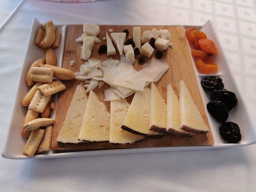 A cheese board with various cheeses, crackers, and dried fruits.