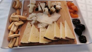 A cheese board with various cheeses, crackers, and dried fruits.