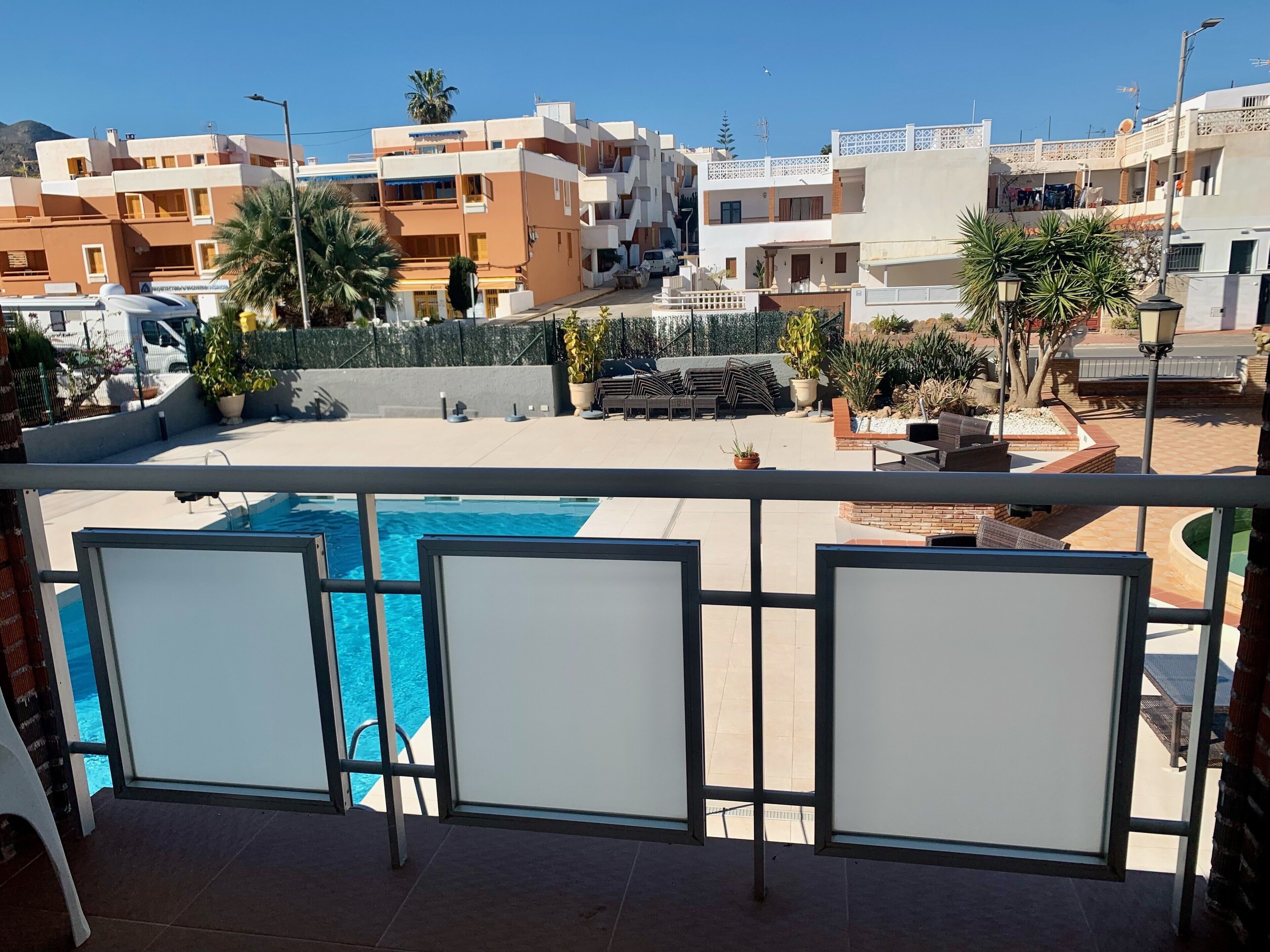 A residential area with a swimming pool, multiple buildings, and outdoor furniture.