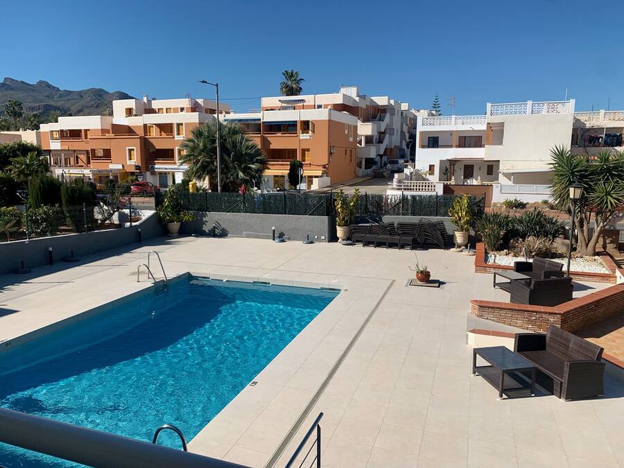A rooftop pool area with a clear blue pool, lounge chairs, and potted plants.