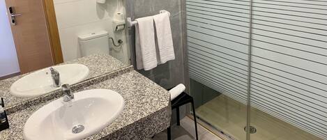 Un baño moderno con dos lavamanos, cabina de ducha de vidrio y un inodoro.