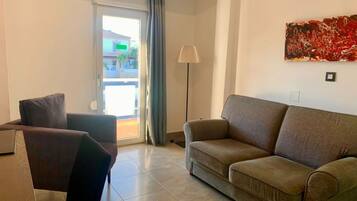 Una sala de estar con un sofá, un sillón, una lámpara y un cuadro en la pared.