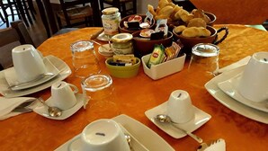 Una mesa con tazas blancas, cucharas y un bol de pasteles.