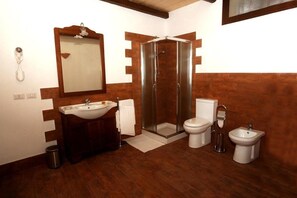 A bathroom with a wooden vanity, a glass-enclosed shower, a toilet, a bidet, and a mirror. - B&B Kephale (Catania)