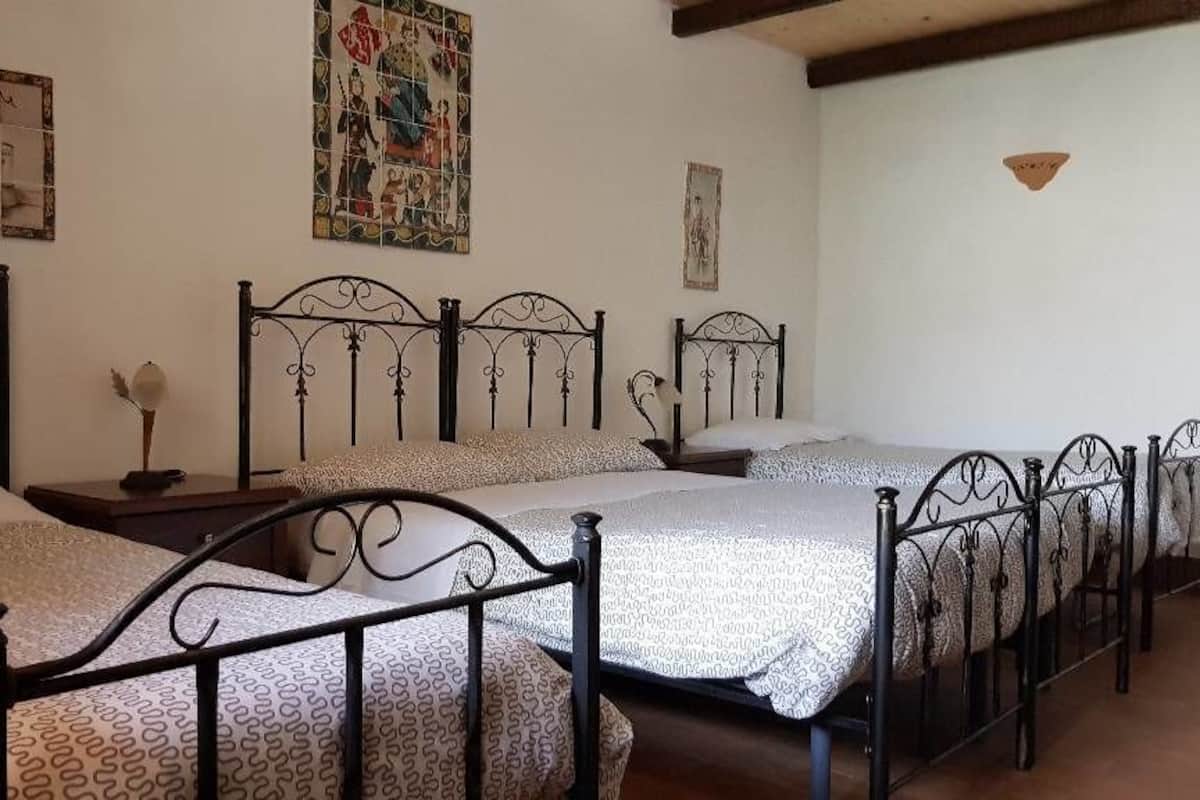 A bedroom with four beds, each with a patterned bedspread and black metal headboards.