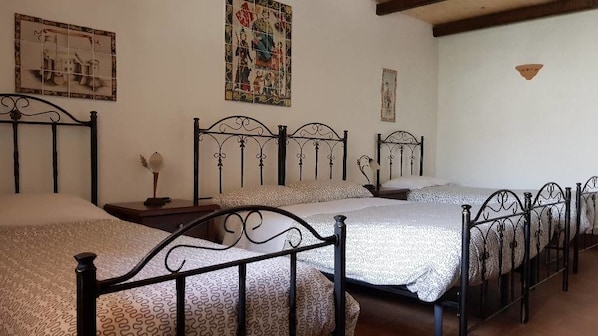 A bedroom with four beds, each with a patterned bedspread and black metal headboards. - B&B Kephale (Catania)