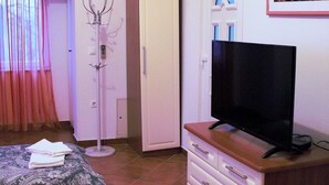 A bedroom with a bed, a dresser, a television, a coat rack, and a door. - Apartments sv. Anton (Kastav)