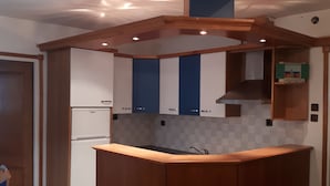 A compact kitchen with wooden cabinets, a built-in stove, and a small island. - Apartments sv. Anton (Kastav)