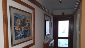A hallway with wooden paneling, a framed painting, a cabinet, and a door with a window. - Apartments sv. Anton (Kastav)