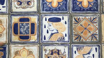 Eine mit verschiedenen geometrischen und floralen Mustern, darunter Kreuze und Gesichter, versehene Wand.