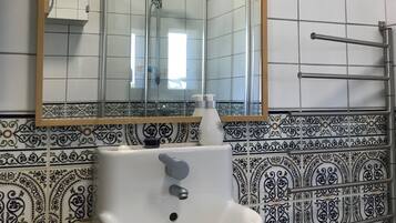 A bathroom with a white sink, a mirror, and a shower.