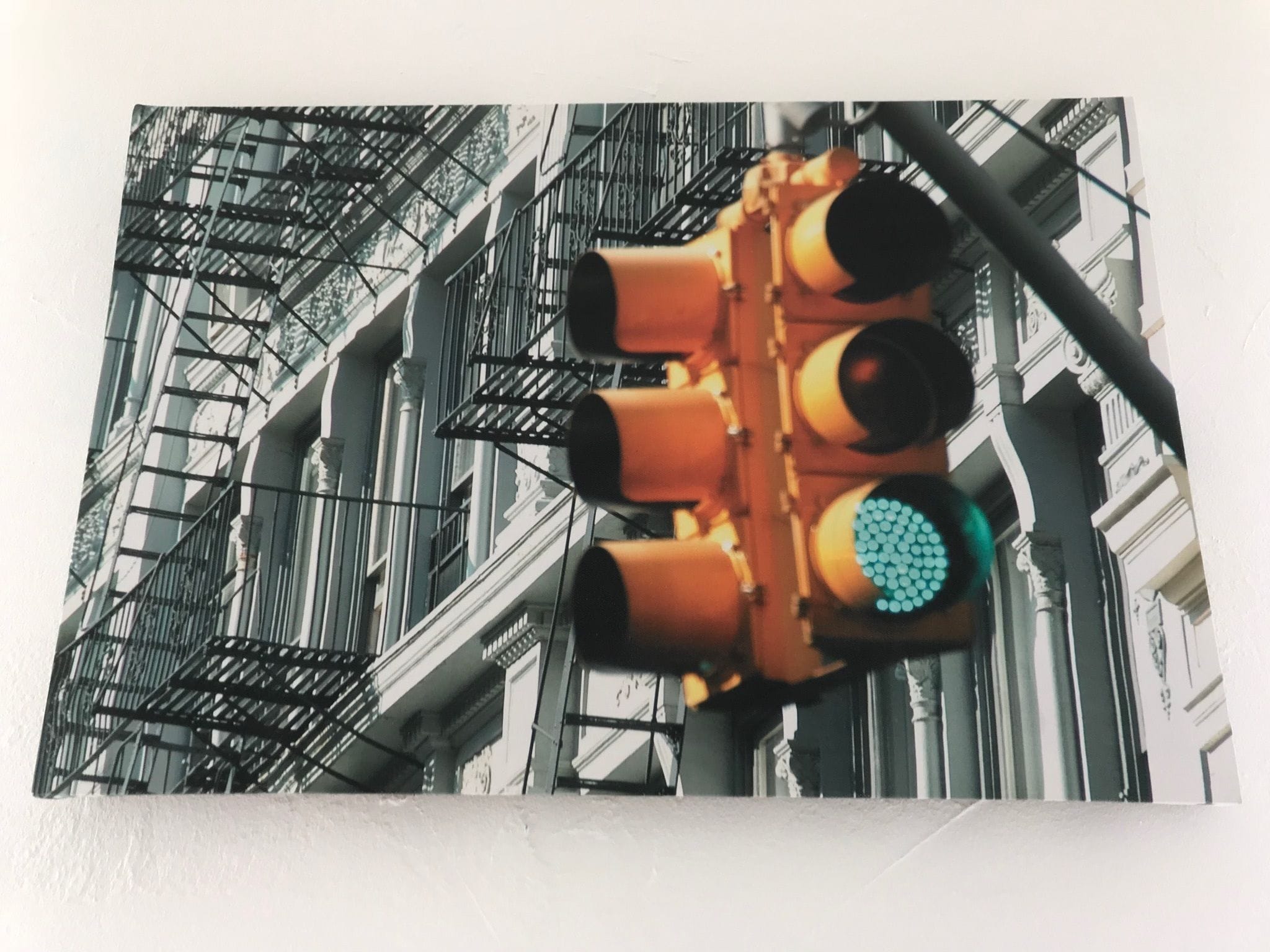 A traffic light with a green signal against a building facade with fire escapes.