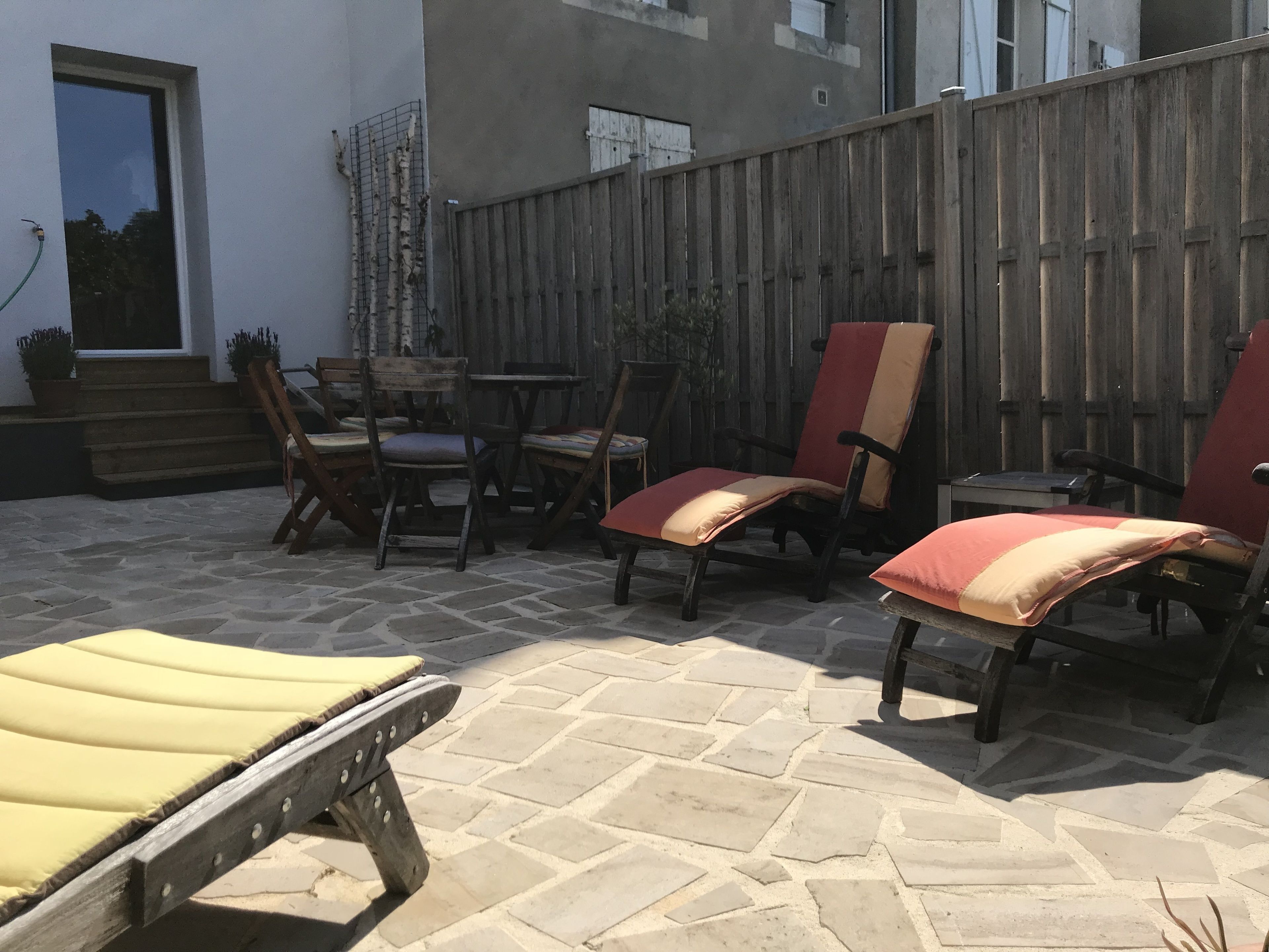Ein Terrassenbereich im Freien mit Steinböden, Holzstühlen und einem Holztisch.