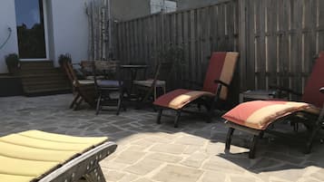 Ein Terrassenbereich im Freien mit Steinböden, Holzstühlen und einem Holztisch.